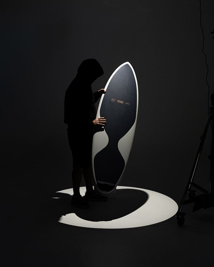 A Mick Fanning Softboard held upright in a pool of studio light